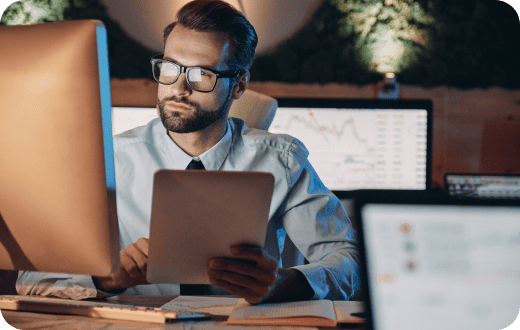 Un joven ejecutivo de barba y gafas, trabaja con una PC de escritorio en el interior de una sala de reuniones. 