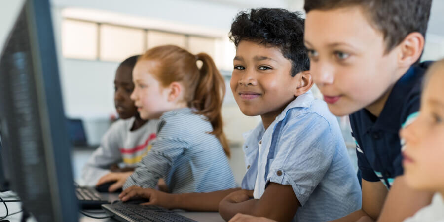 Un grupo de niños se divierte mientras aprende usando computadoras en el interior de un aula interactiva. 