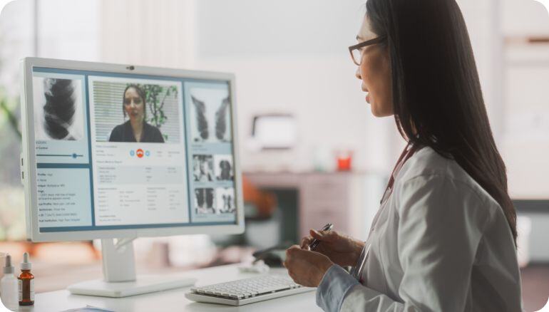 Una médica comparte sus impresiones sobre un diagnóstico con una colega a través de una videollamada con un equipo de escritorio. La doctora es afroamericana y su colega es latina. 