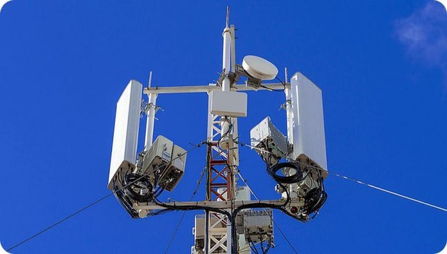 Vista en contrapicada de una alta antena para radioenlaces. Al fondo de aprecia un cielo claro. 