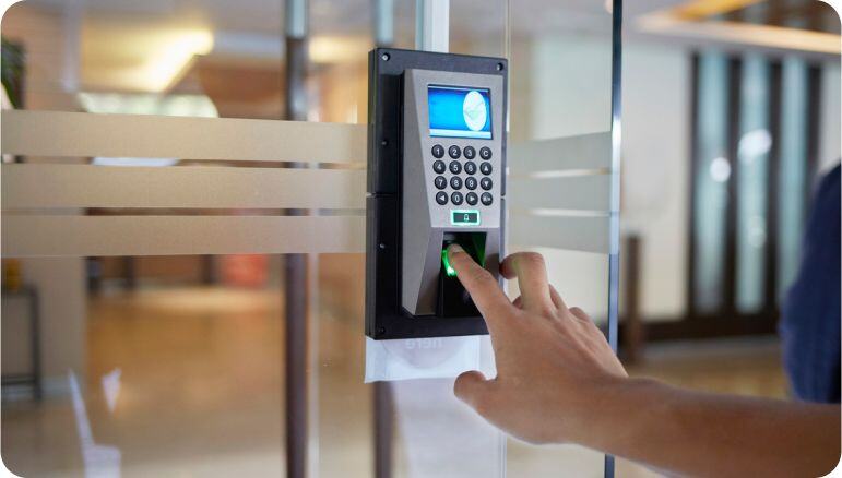 Una mano masculina coloca su dedo en el biométrico de un control de acceso automático en el interior de una oficina.