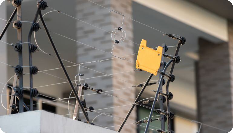 Imagen de una cerca electríficada arriba de una barda industrial. 