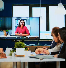 En una sala de reuniones, un grupo de colaboradores están reunidos para una videollamada 