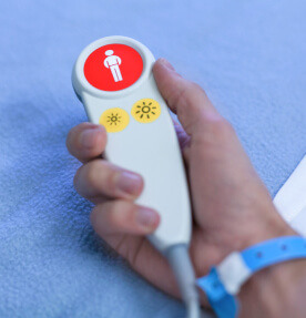 La mano de un paciente porta un dispositivo para el llamada de enfermería. 