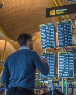 Un pasajero mira los monitores de próximas salidas en el interior de un aeropuerto. 