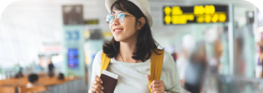 Una turista asiática mira con atención los señalamientos digitales de un aeropuerto. 