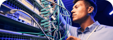 Un ingeniero de TI revisa el cableado de un equipo de networking dentro de un centro de datos 