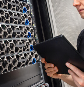 Imagen de un ingeniero de TI revisando el funcionamiento de un servidor utilizando una tablet. 