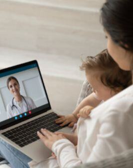 Una madre y su bebé consultan a un médico a través de una videollamada con una laptop. 